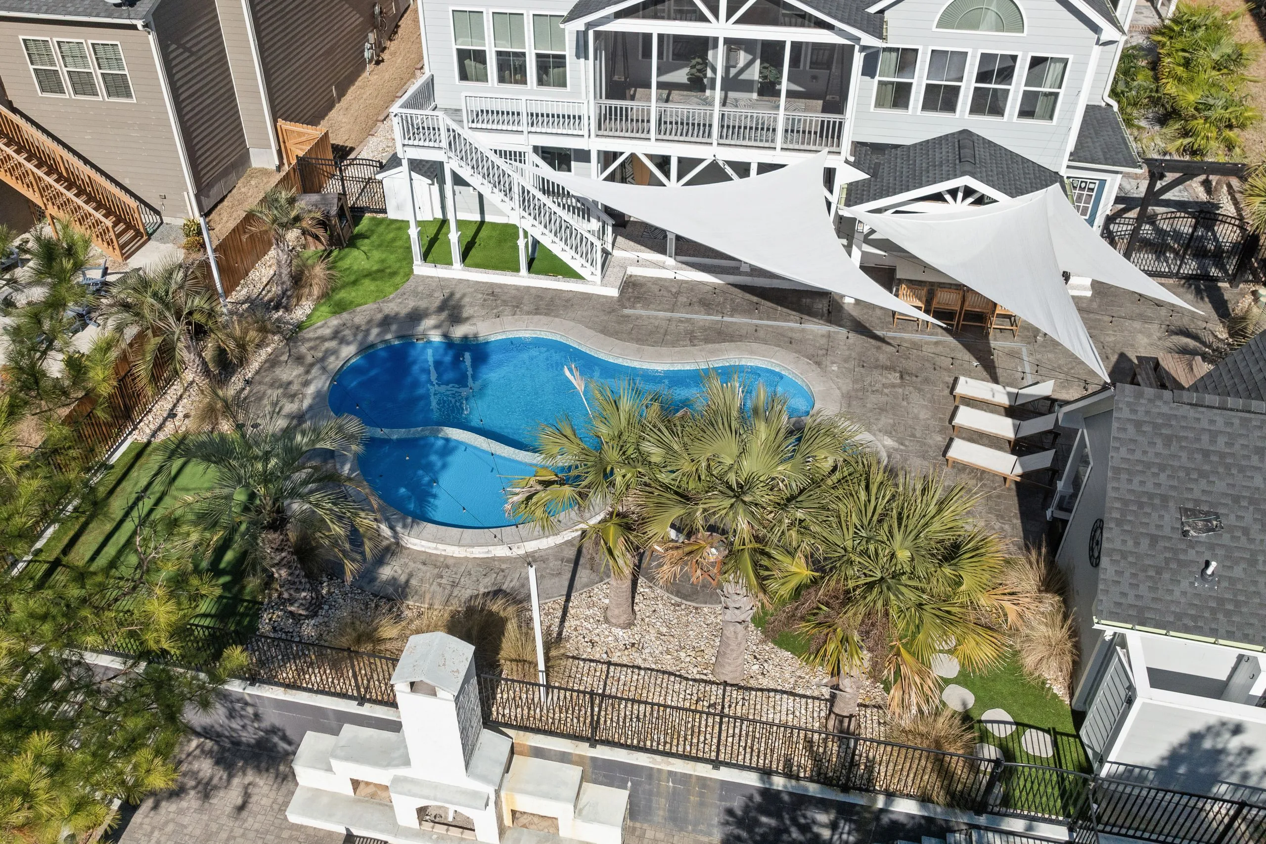 Vue d'une piscine lagon au jardin avec plage immergée en pente douce, eau turquoise et pierres naturelles.